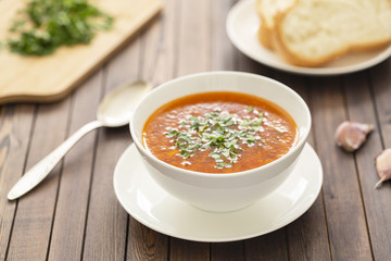 Chicken soup with vegetables and herbs in a white bowl on a wooden table