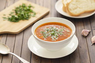 Chicken soup with vegetables and herbs in a white bowl on a wooden table