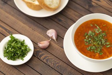 Chicken soup with vegetables and herbs in a white bowl on a wooden table