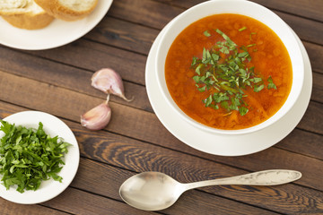 Chicken soup with vegetables and herbs in a white bowl on a wooden table