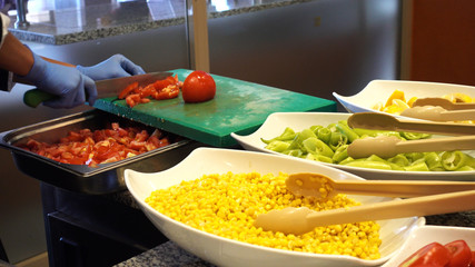 The chef cuts the tomatoes. Cut vegetables and greens as ingredients for salads.
