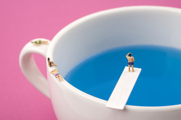 miniature people in mug cup swimming pool