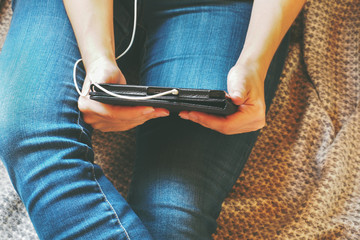 Legs in jeans, tablet in hands on a gray blanket. Concept training and recreation.