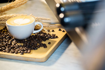 Focused coffee cup on wood table with coffee beans and spike on background.  daily aroma drinking concept. coffee latte art image for decoration, interior design background, wallpaper and copy space.
