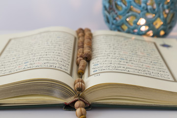 Quran and rosary on the white background with blue candle for Islamic concept. Holy book Koran for Muslims holiday, Ramadan,blessed Friday message and three months