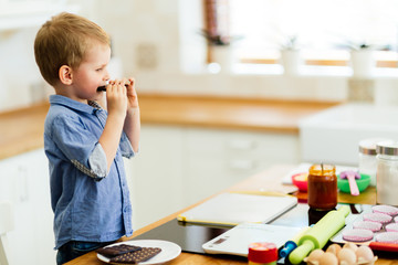 Child tasting chocolate bar in kitchen
