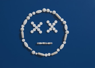 Pills forming dizzy face on blue background