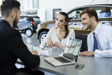 Insurance broker or salesman making offer to young millennial couple using laptop in cafe, realtor consulting customers about mortgage sitting at coffeehouse table pointing on computer screen.