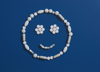 Pills forming smiley face on blue background