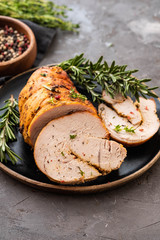 Stuffed turkey breast with baked vegetables and spices on a black background.