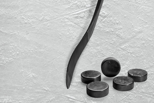Black hockey stick and ice hockey pucks on ice