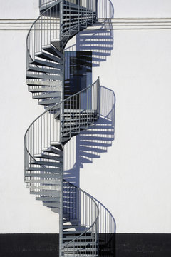 Spiral staircase and door along sunny wall