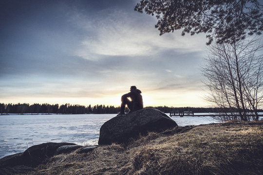 Man sitting on rock overlooking Lake Nydala, Umea, Sweden