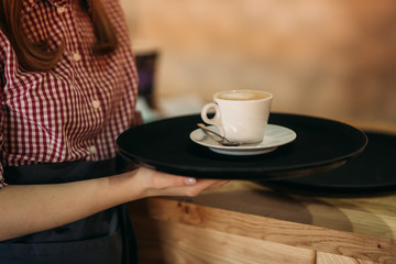 Waitress offering a cup of coffee in cafe. cappuchino
