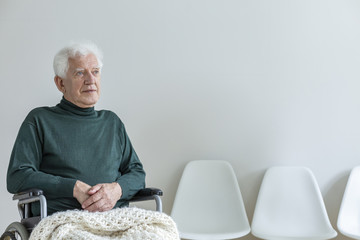 Paralyzed man in a wheelchair in a waiting room in a hospital