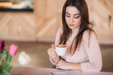 Beautiful girl siting in cafe and drinking cappuccino