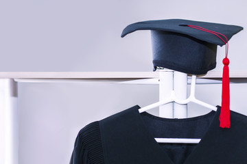 Congratulate graduate.Graduation gown and black hat on white background.