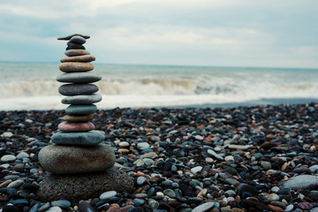 relaxation at sea. Stack of stones on beach - nature background. Stone cairn on green blurry...