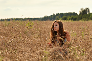 in the rays of a serene evening sunset on a wheat field behind the spikelets is a girl in a retro...