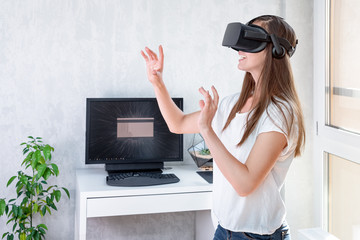 Smiling positive woman wearing virtual reality goggles headset, vr box. Connection, technology, new generation, progress concept. Girl trying to touch objects in virtual reality