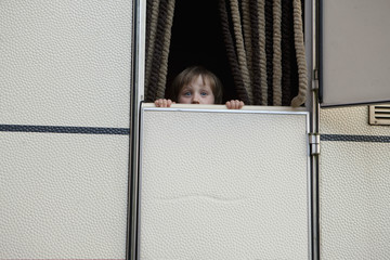Portrait cute, curious girl peeking from behind trailer door