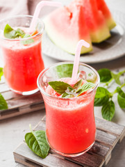 Fresh watermelon smoothie with ice and mint leaves in glasses.