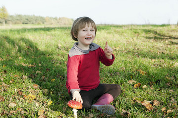 Portrait happy girl sitting next to mushroom