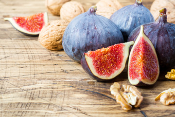 Fresh figs whole and cut with walnut kernels on a wooden old background. copy space