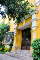 A beautiful old yellow building is decorated with green plants