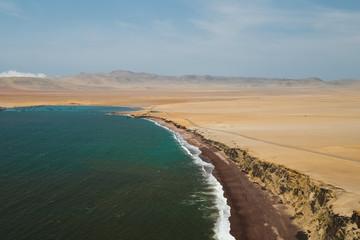 Fototapeta premium Natural reserve in Paracas, Peru. Blue sky, green sea, yellow cliffs, desert and ocean