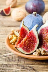 Fresh figs whole and cut kernels of walnuts on a plate the old wooden background.