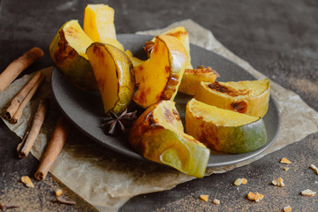 Baked pumpkin with spices in a plate on a dark background