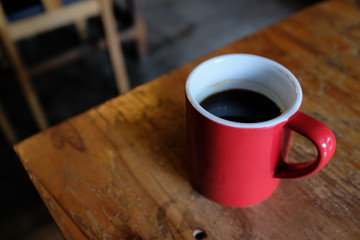 High angle view of a red cup of coffee on a rustic wooden table in a cafe with blurred background