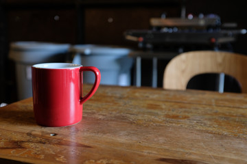 Zoom out of a red cup of coffee on a rustic wooden table in a cafe with blurred background