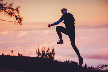 Silhouette of athlete in nature. Man watching sunset in mountains by beautiful lake. Sport photo, edit space. High Tatras Slovakia. Morning warm up concept photo