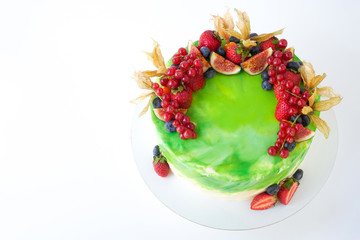 Cake with whipped green cream, decorated with fresh strawberries, blueberries, figs and physalis on white background. Picture for a menu or a confectionery catalog. Top view.