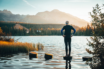 Silhouette of athlete in nature. Man watching sunset in mountains by beautiful lake. Sport photo, edit space. High Tatras Slovakia. Morning warm up concept photo