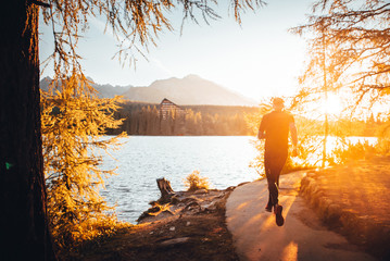 Silhouette of athlete in nature. Man watching sunset in mountains by beautiful lake. Sport photo, edit space. High Tatras Slovakia. Morning warm up concept photo