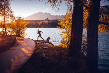 Silhouette of athlete in nature. Man watching sunset in mountains by beautiful lake. Sport photo, edit space. High Tatras Slovakia. Morning warm up concept photo