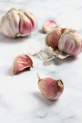 Garlic heads and cloves on white marble surface