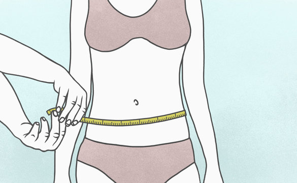 Woman measuring waist with tape measure