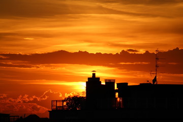 Fototapeta na wymiar Urban sunset: sun going down with orange sky behind city buildings