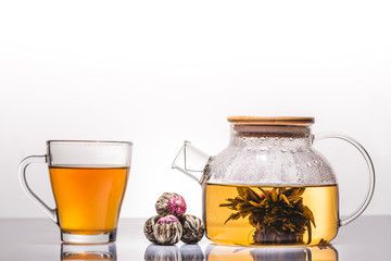 cup and teapot of chinese flowering tea with tea balls on table