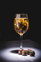 glass of traditional chinese flowering tea with tea balls on table isolated on black
