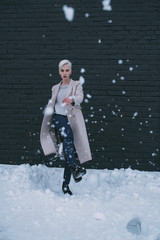 Portrait young woman kicking snow