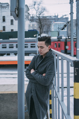 Young man in coat standing at winter railroad station