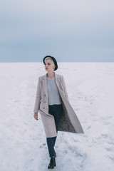 Woman in coat and hat walking in snow covered landscape