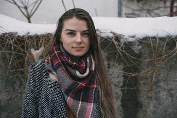Portrait young woman in plaid scarf against snow covered wall