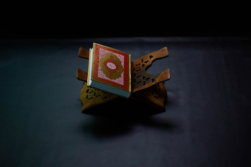 Quran in the mosque - open for prayers The black background of the Muslims around the world placed on a wooden board Quran in the mosque - open for prayers Black background