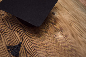 Graduate cap on the wooden school desk with copy space.